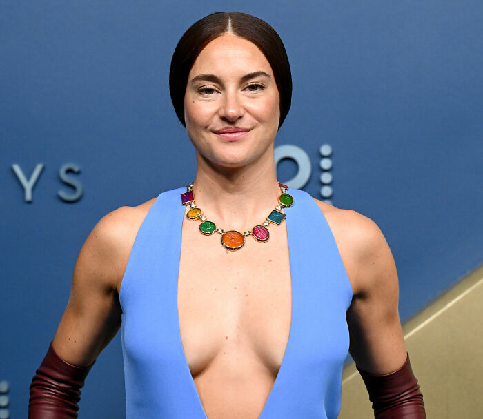 Shailene Woodley&rsquo;s Emmys outfit featuring a colorful necklace, deep V-neck top, and dark red gloves on the red carpet.