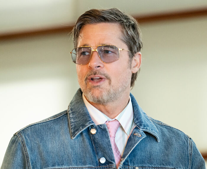 Brad Pitt wearing sunglasses and a denim jacket looking concerned about Zahara Jolie-Pitt.