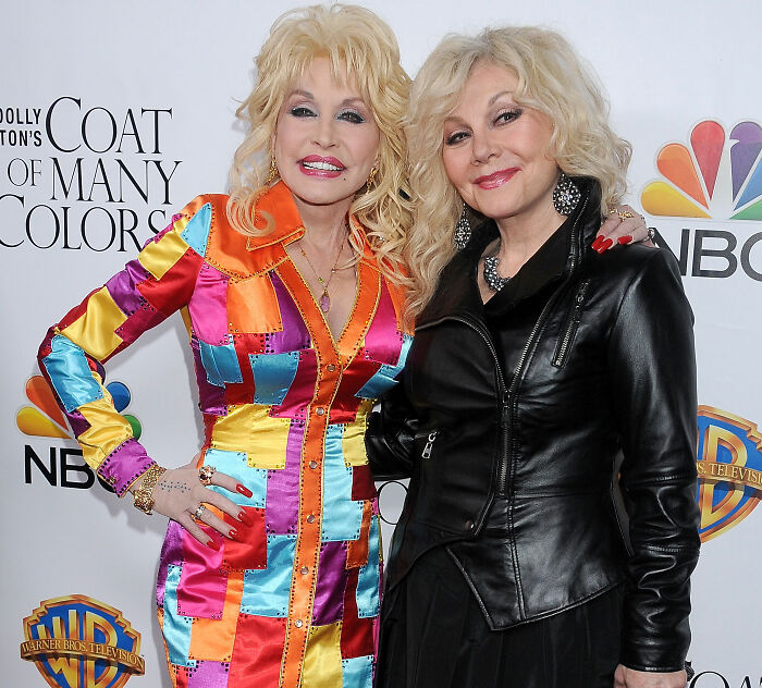 Dolly Parton standing beside a blonde woman on a red carpet event Dolly Parton standing beside a blonde woman on a red carpet event