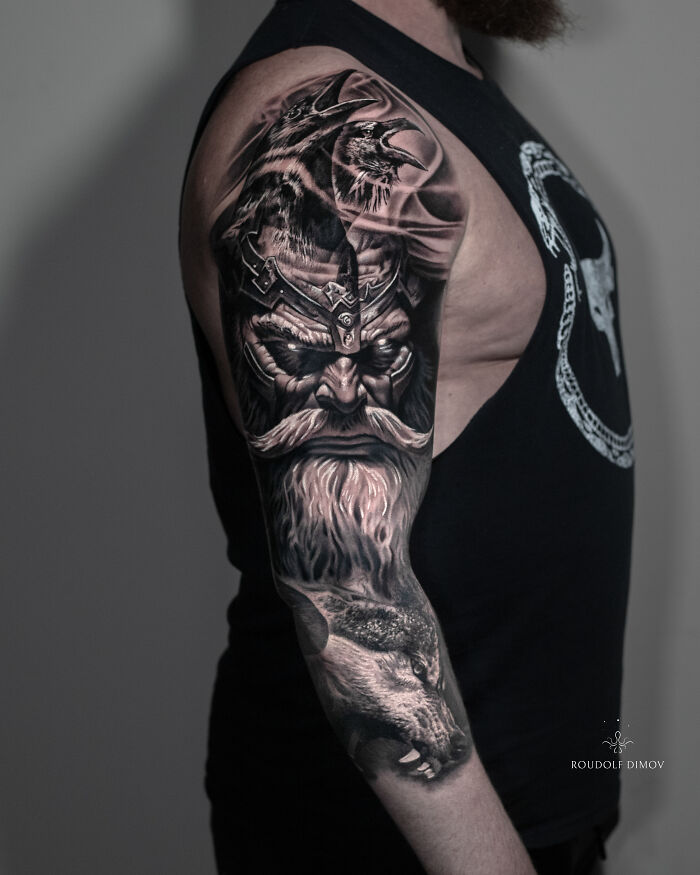 Stunning mythology tattoo of a bearded warrior and wolf on a mans arm, from Sacred Gold Studio.