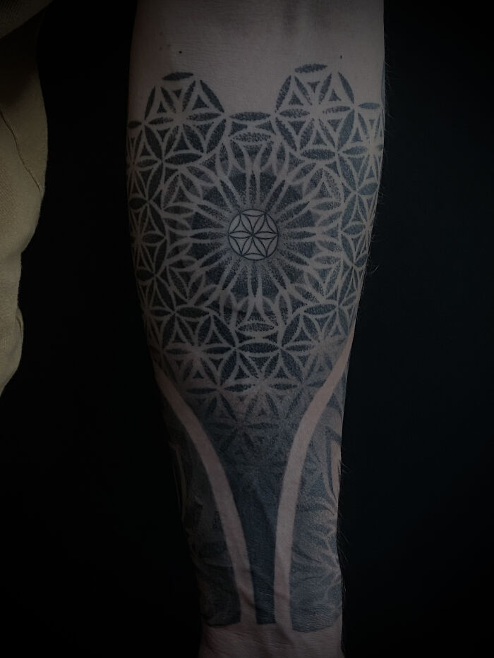 An intricate spiritual geometry tattoo covering an arm with geometric patterns from Sacred Gold Studio.