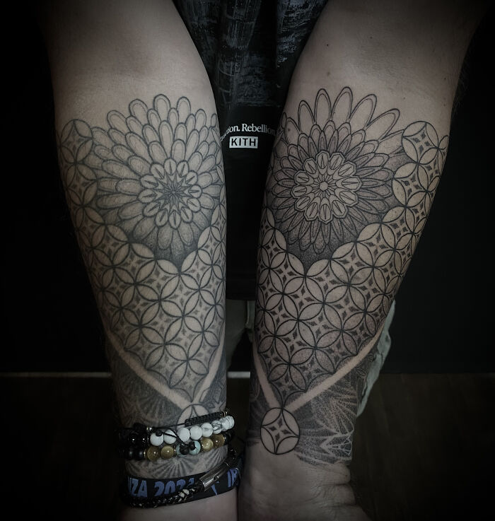 Two forearms adorned with matching spiritual geometry tattoos featuring mandala-like designs from Sacred Gold Studio.