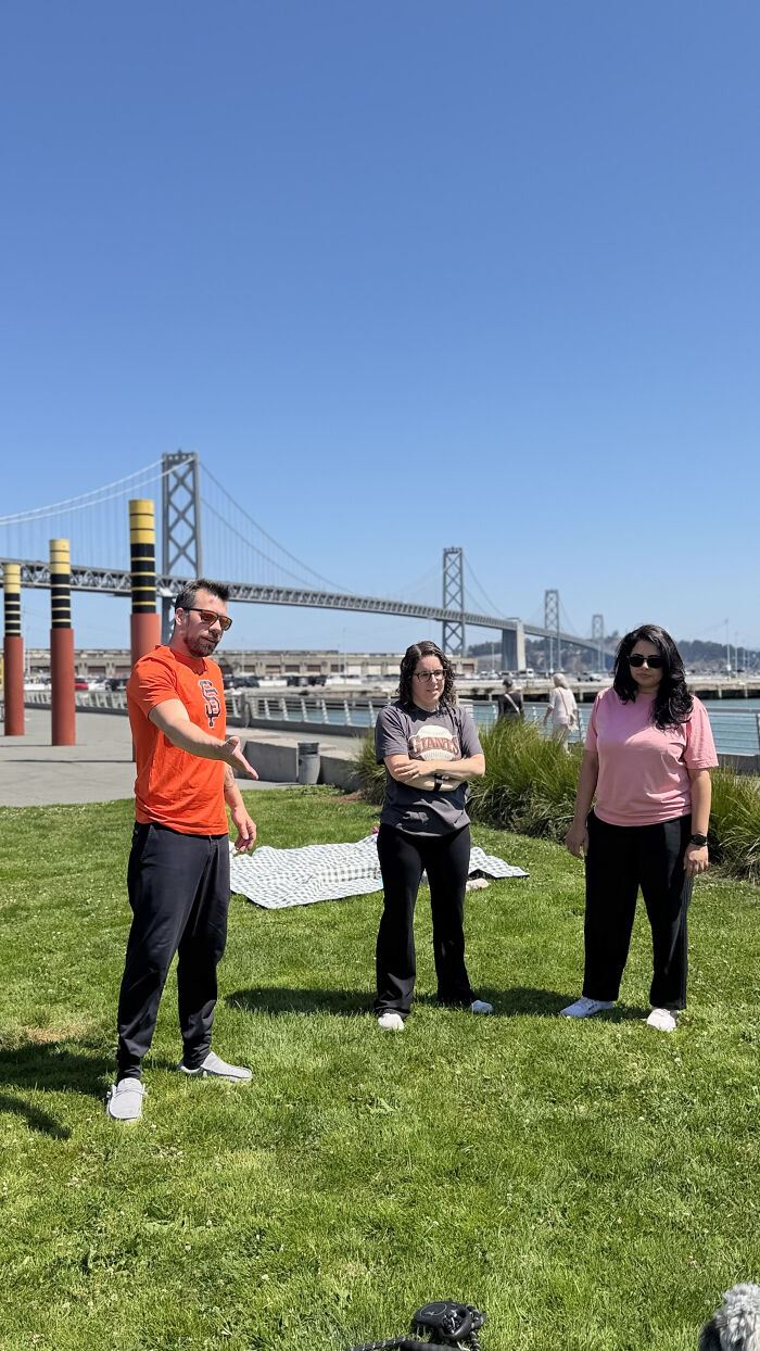 Three individuals stand in a grassy park, part of a community supporting pet owners and their dogs. Three individuals stand in a grassy park, part of a community supporting pet owners and their dogs.