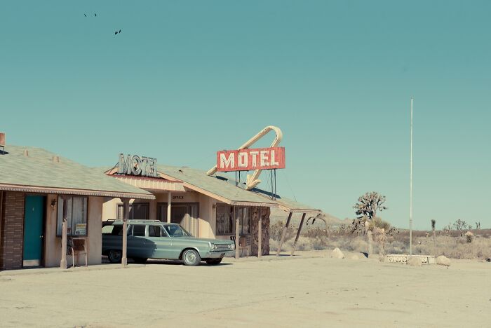 A classic car parked in front of a retro motel with a prominent Motel sign, capturing the bygone American West.