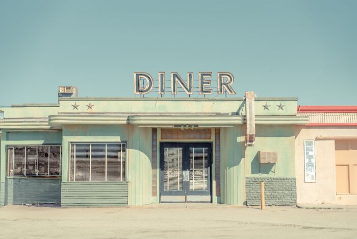 A vintage diner facade with a large sign, showcasing the rusty remnants of the American West.