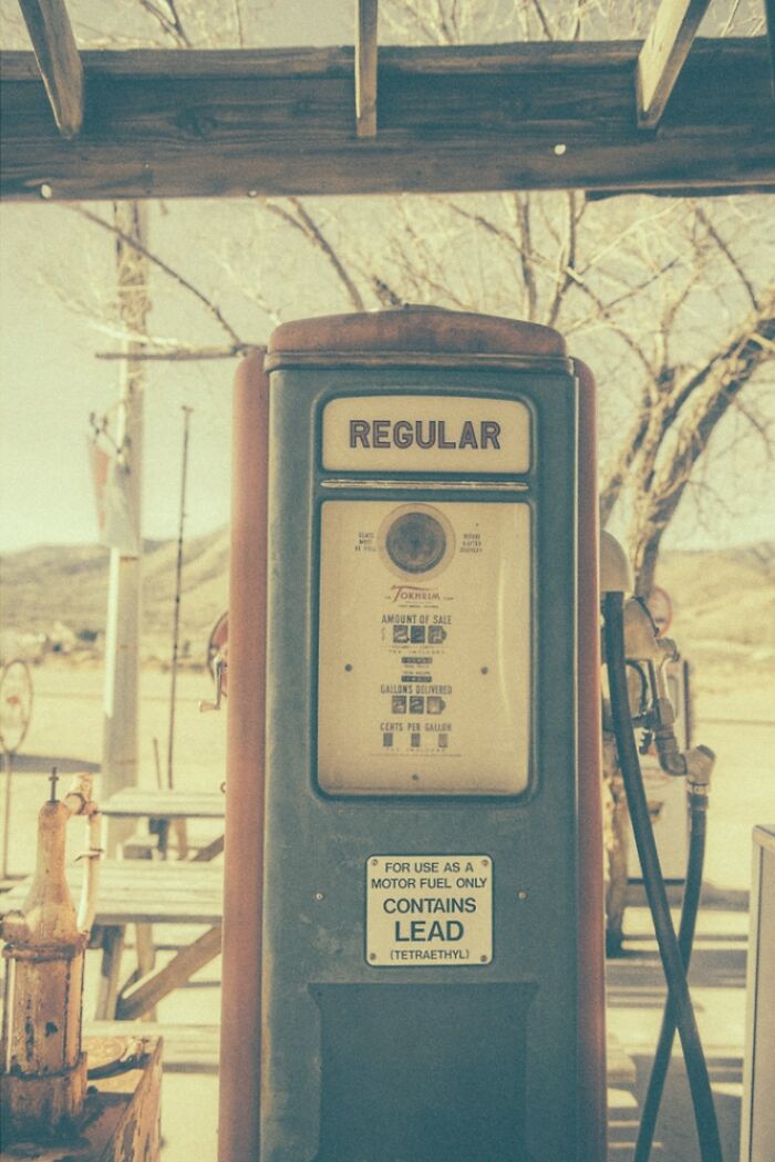 A vintage regular gas pump, rusty and dusty, standing in a bygone American West setting.