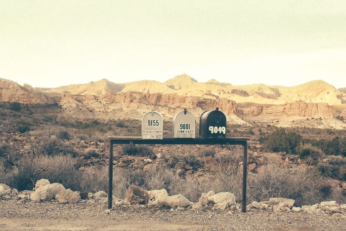 Three mailboxes in the dusty American West, showing remnants of a bygone era with mountains in the background.