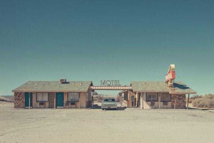 A photographer captures the rusty, dusty remnants of an American West motel in a vintage-style photograph.