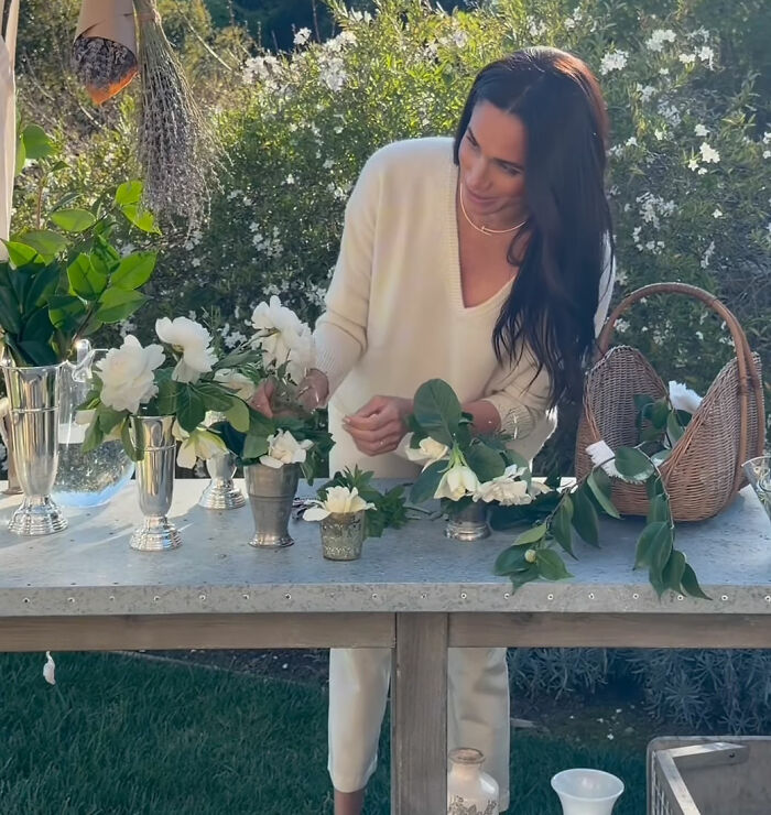 Meghan Markle arranging flowers at an outdoor table, potentially reflecting on her interview rules. Meghan Markle arranging flowers at an outdoor table, potentially reflecting on her interview rules.