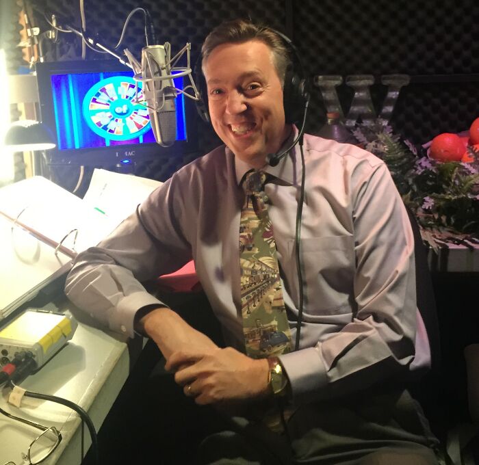 A man smiling in a recording studio with a microphone, symbolizing dumb ways people ruin their lives.
