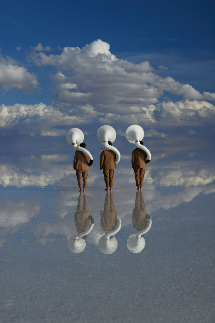 Surreal art photo of three tubists standing barefoot on reflective surface under dramatic clouds