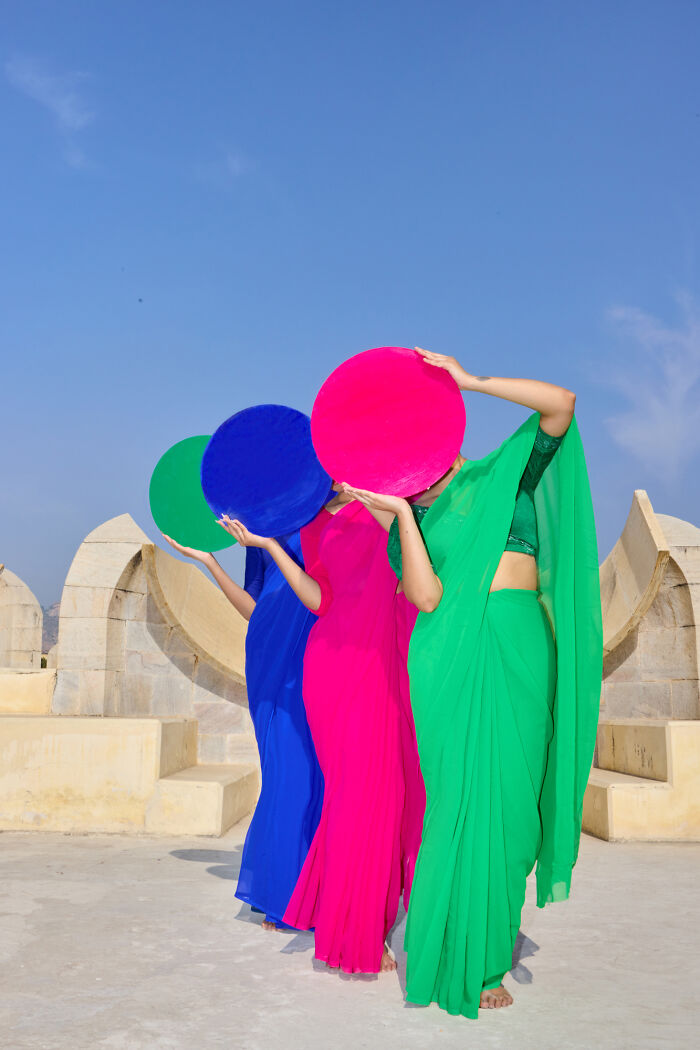 Surreal art expedition image of three women in colorful sarees holding circular discs
