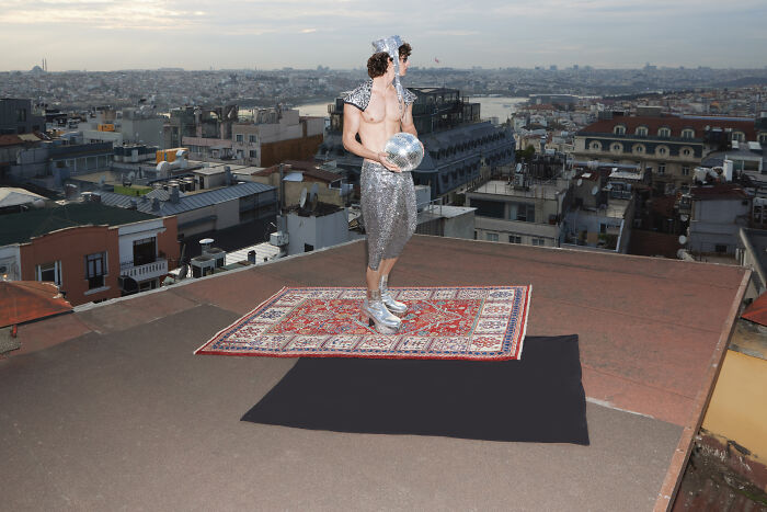 Surreal art expedition photo of a man in silver outfit on rooftop carpet in cityscape
