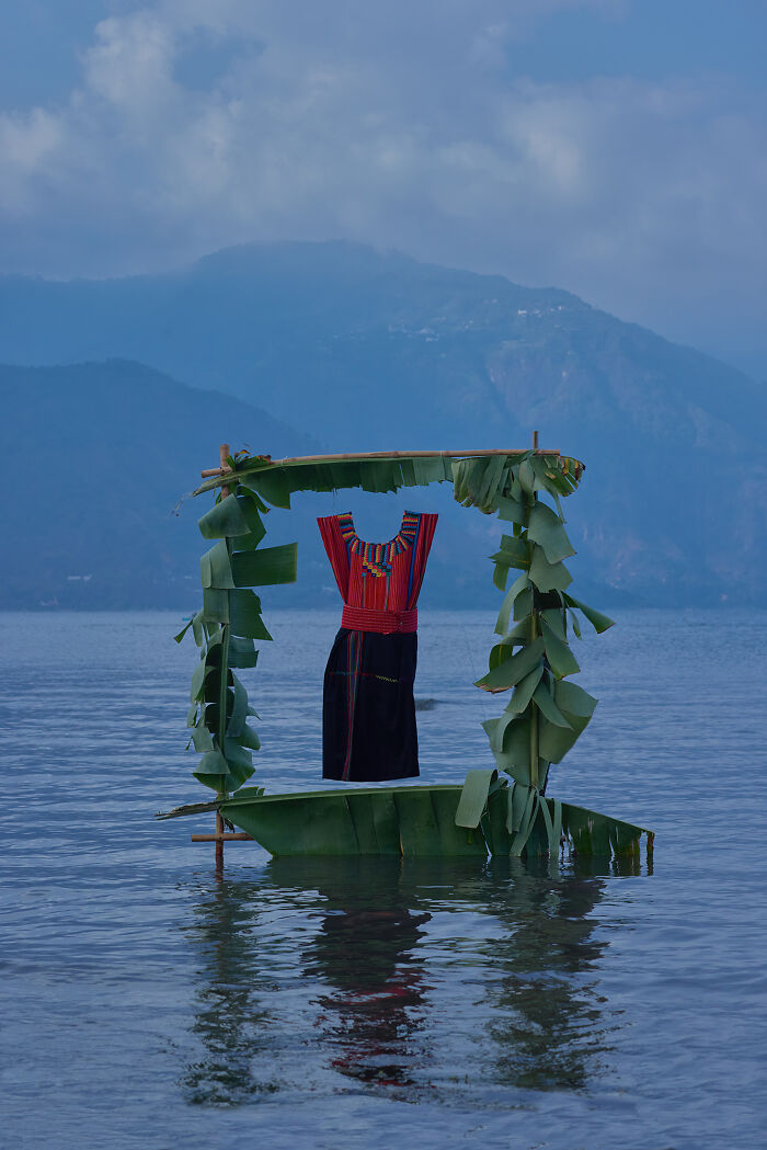 Surreal art installation featuring traditional dress framed by banana leaves on water