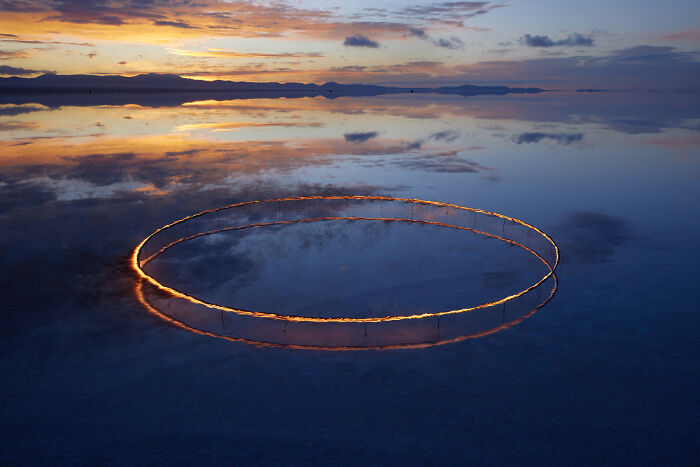 Surreal art expedition image of glowing circle on reflective water at sunset