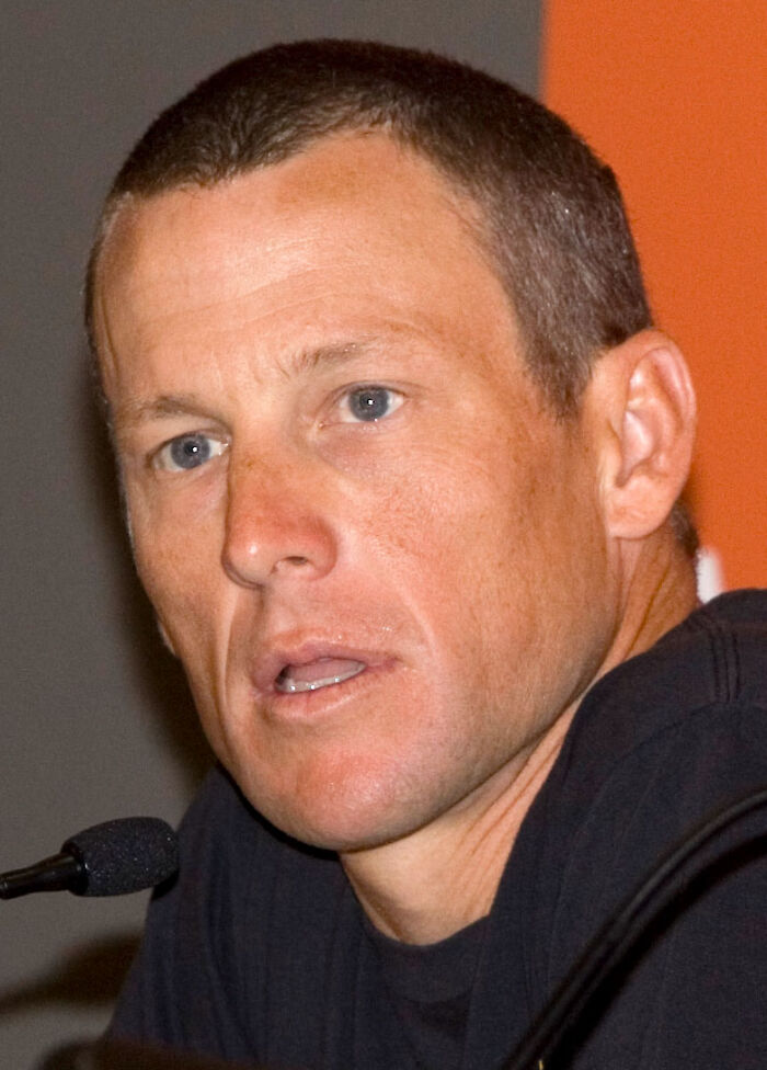 Lance Armstrong, a public figure, speaking into a microphone, known for destroying his legacy.