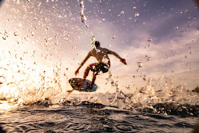 A surfer leaps from an ocean wave at sunset, capturing stunning images from the Ocean Photographer of the Year Awards.