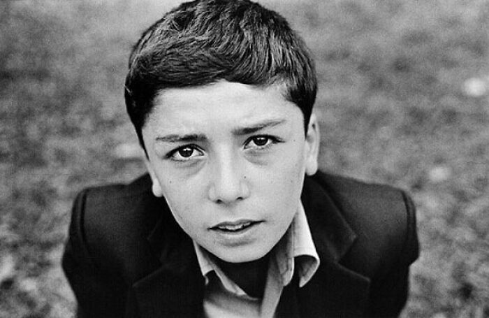 A Murat Harmanlikli street photo showing the intensity and curiosity of childhood with a boy looking up at the camera.