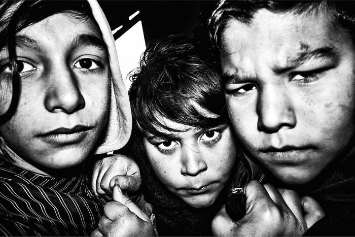 Street photos showing the curiosity and intensity of childhood with three young children looking directly at the camera.