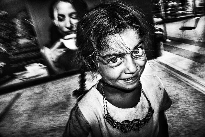 A black and white street photo by Murat Harmanlikli capturing the joy and curiosity of childhood.