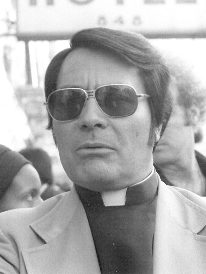 A grayscale photo of a public figure, Jim Jones, wearing sunglasses and a clerical collar.