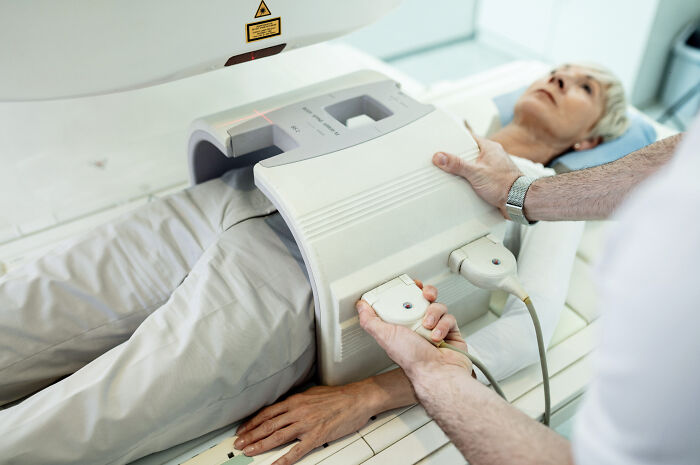 A nurse tending to a senior woman in a medical scanner. Doctors and nurses often see various pain reactions.