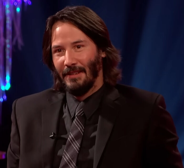 Keanu Reeves smiling, showing a positive reaction to celebrity hot takes.