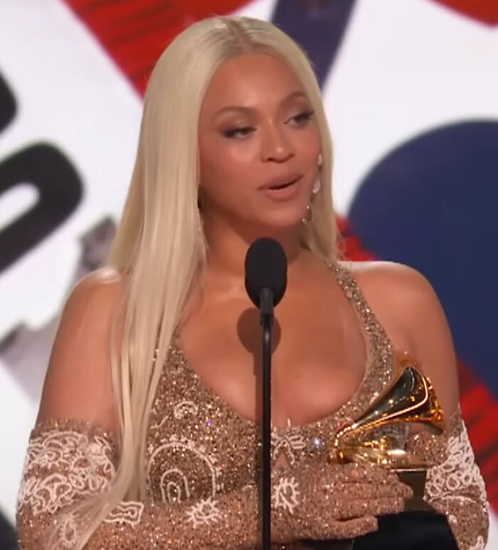 Beyoncé with long blonde hair, holding a Grammy, offering a brutal hot take on celebrities.