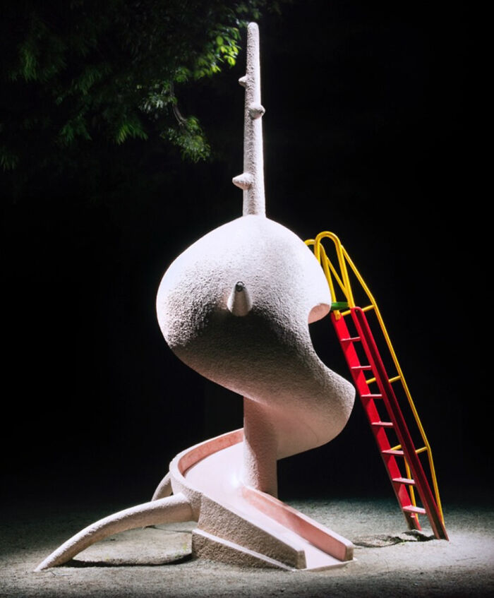A surreal Japanese playground at night featuring a white, spiraling slide next to a red and yellow ladder, by Fujio Kito.