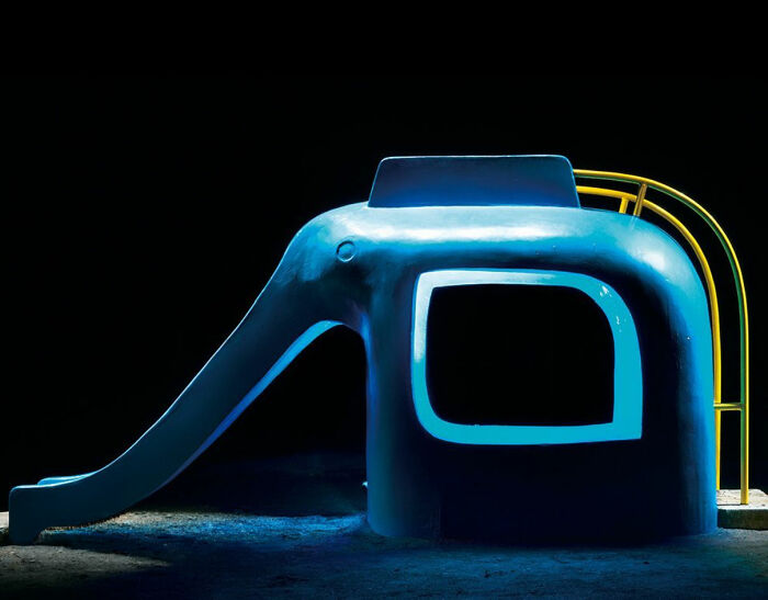 Surreal Japanese playground at night featuring an elephant-shaped slide with glowing details, captured by Fujio Kito.