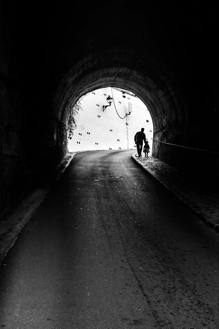 A street photographer captured an odd coincidence: a man and child walking through a dark tunnel towards a bright light.