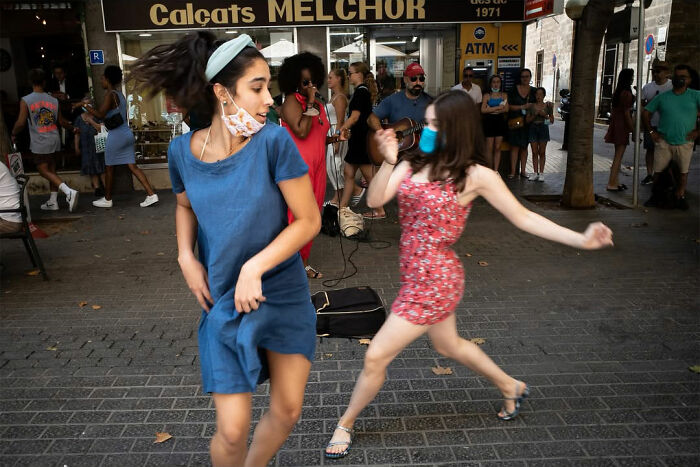 A street photographer captures two women dancing on a street, part of the odd coincidences and scenes in public.