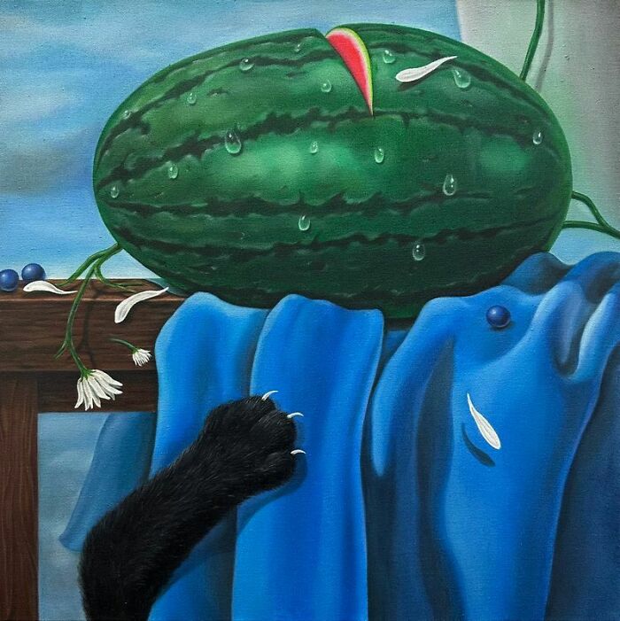 A black cat's paw stretches towards a surreal watermelon with a single slice removed, next to blue fabric.