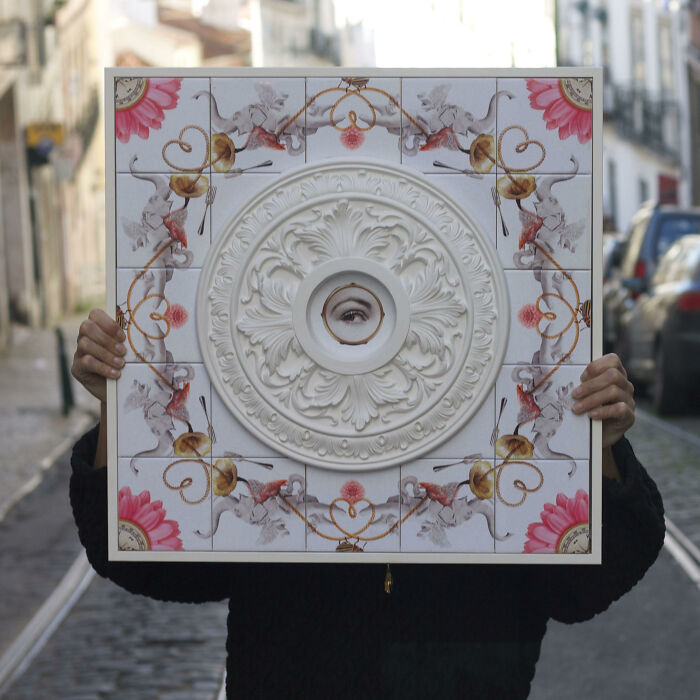 Person holding tile works art piece with eye and floral design outdoors