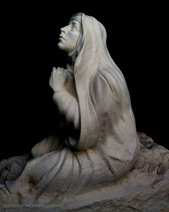 Lifelike wood sculpture of a praying nun with folded hands by a Polish artist