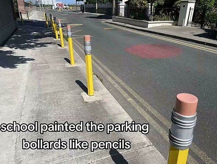 Parking bollards painted like yellow pencils along a sidewalk