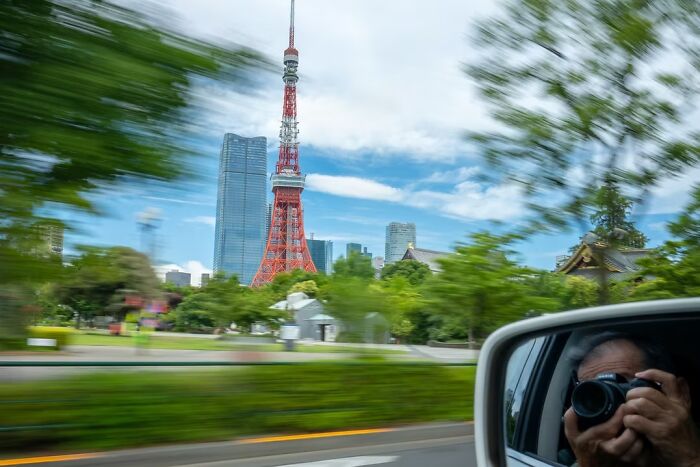 Remarkable travel photos of the Tokyo Tower seen from a car window, with a reflection of a photographer in the mirror.