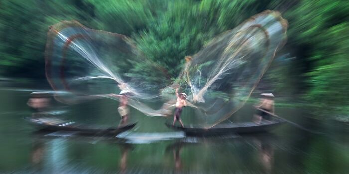 Remarkable travel photos showing fishermen casting nets with motion blur, on a lush green river.