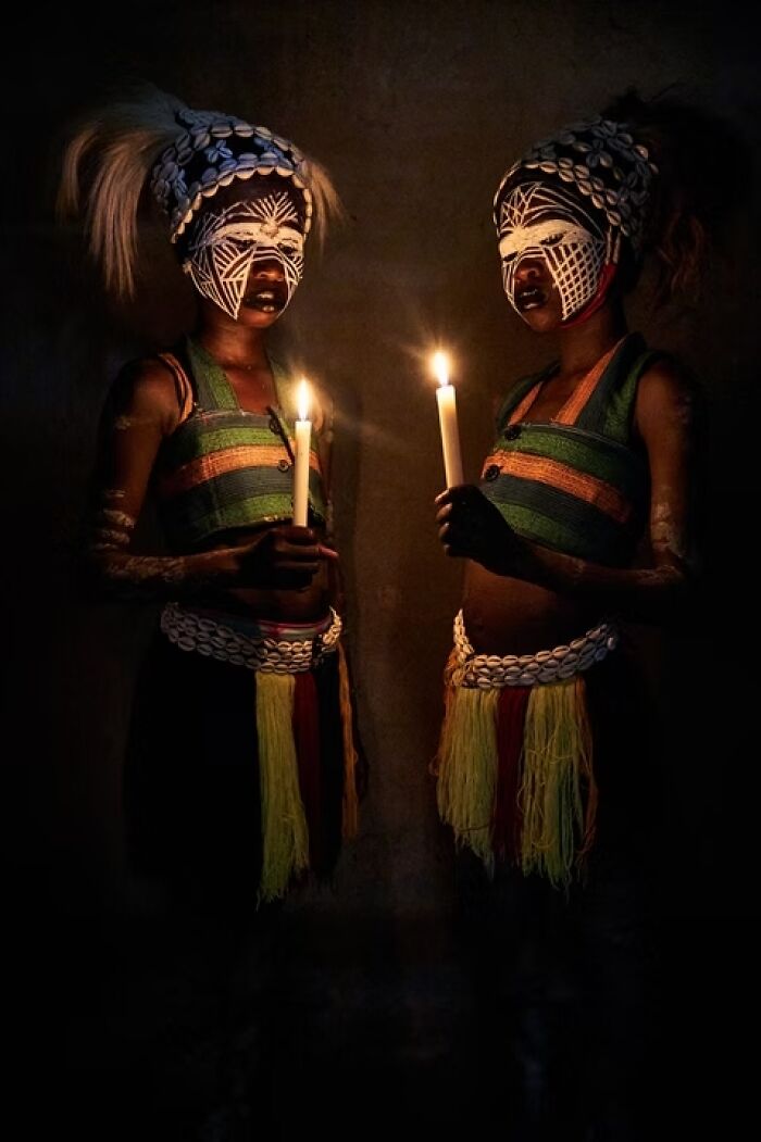 Remarkable travel photos capturing two people with painted faces holding candles, highlighting unique places and people.