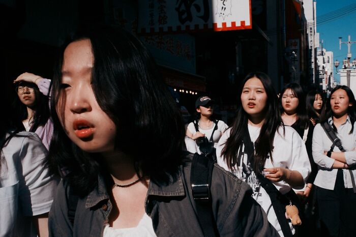 A group of young women walking on a sunny street, capturing candid street photos for URBAN Photo Awards.