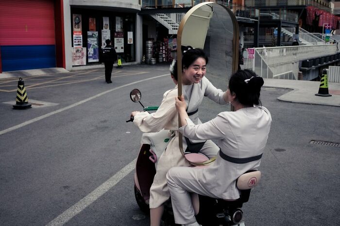 Two women on a scooter with a mirror, captured as candid street photos for URBAN Photo Awards.