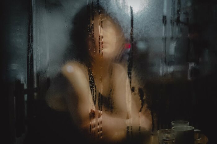 Candid Street Photos of a person's blurry reflection on a foggy window, with glasses and cups on the table.