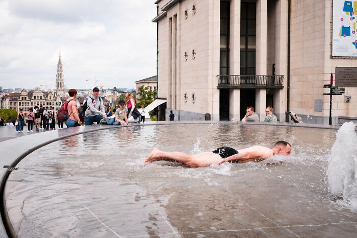 A man swims in a public fountain, a striking candid street photo from the URBAN Photo Awards.