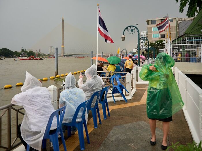 Candid street photo of people in rain ponchos watching a boat race on a river for the URBAN Photo Awards.