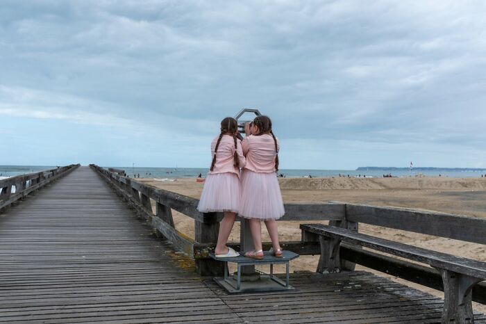 Two girls on a pier looking through a viewer at the ocean, a candid street photo for URBAN Photo Awards.