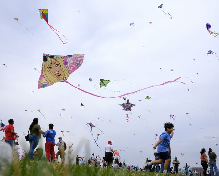 People flying kites in a large open field, a lively candid street photo for URBAN Photo Awards.