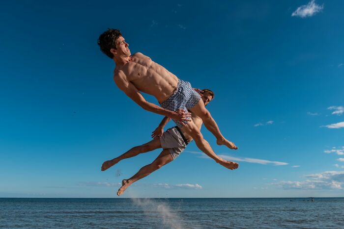A candid street photo of two men mid-air against a blue sky, an entry in the URBAN Photo Awards.