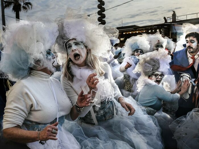 People in elaborate white and blue costumes with dramatic makeup and wigs, captured in a vibrant scene for the URBAN Photo Awards.