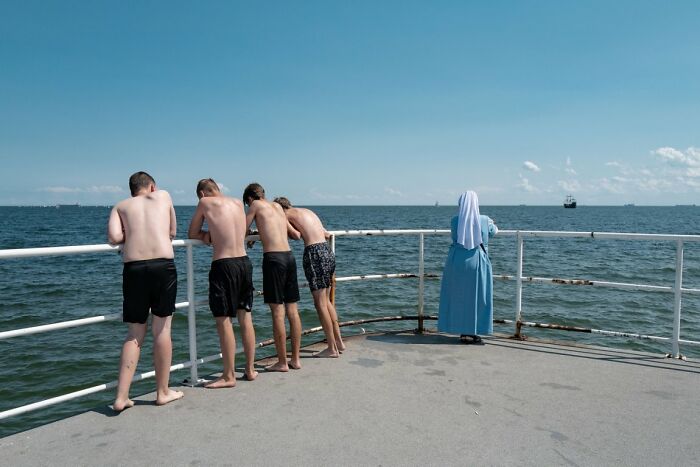 Candid Street Photos of a nun and four shirtless boys looking out at the sea from a pier, URBAN Photo Awards.