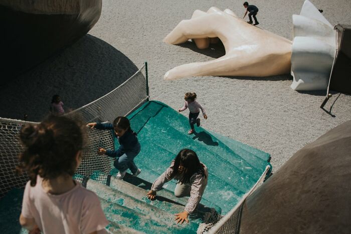 Candid Street Photos of children playing on a giant hand structure in a playground, URBAN Photo Awards.